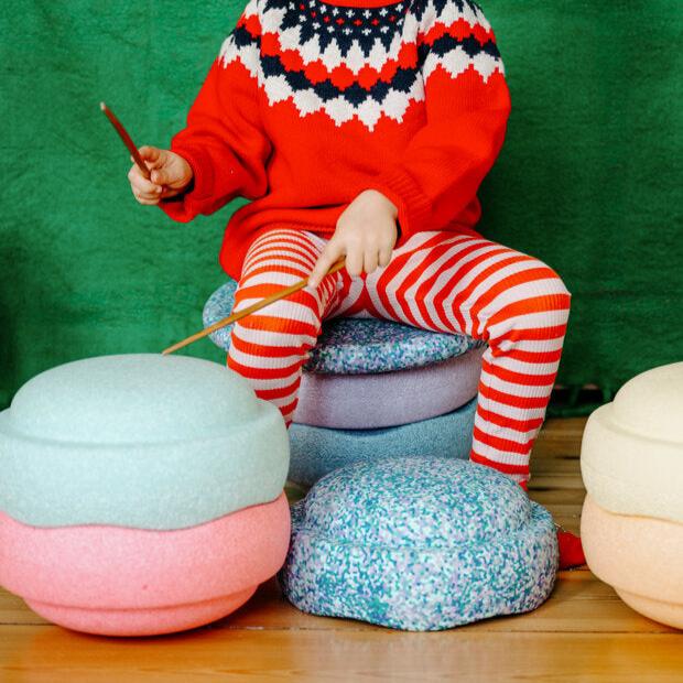 A child puts on a show with the Stapelstein stepping stones fashioned as a drum set and stool.