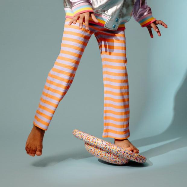 A child steps onto a super confetti Stapelstein® Balance Board.