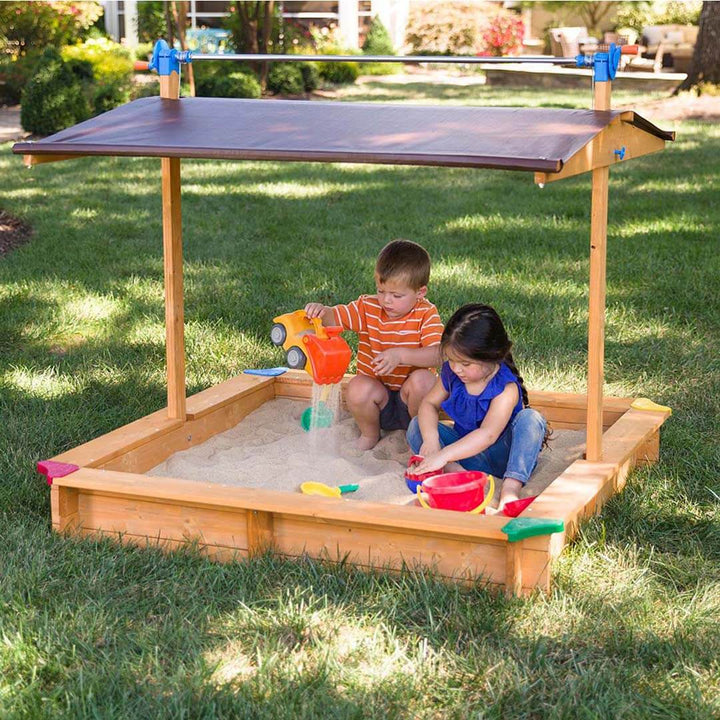 Kids Wooden Sandbox with Cover being played in outside by two kids.