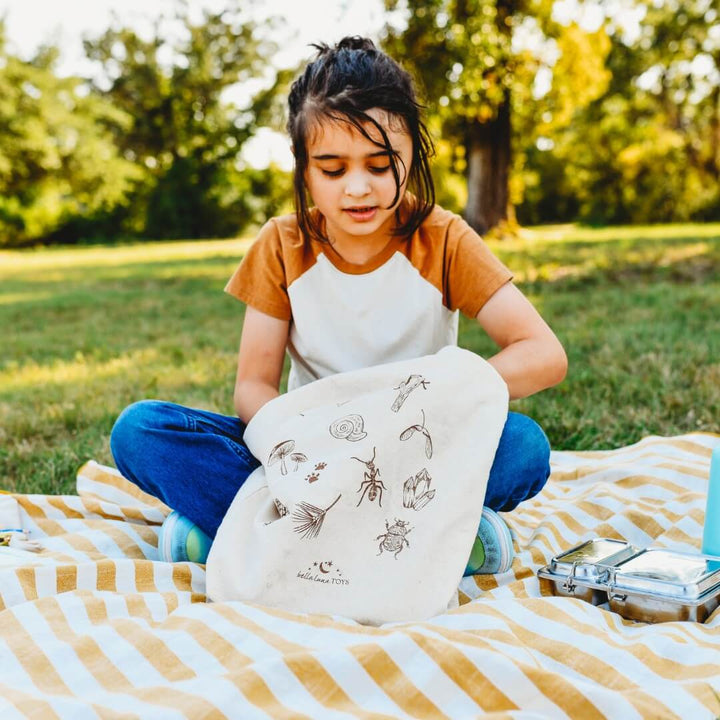 A child is looking for snacks in the Bella Luna Toys Nature Treasure Hunt Book Tote.