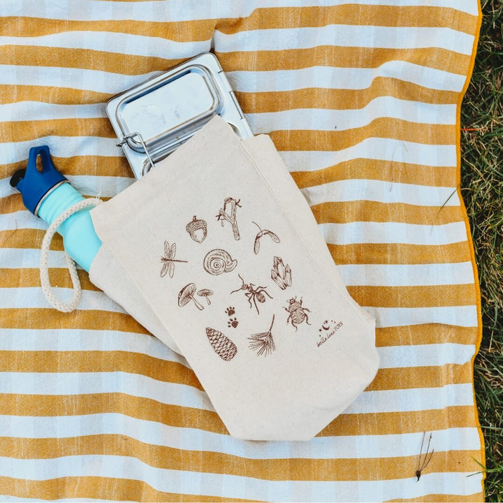 A lunchbox and waterbottle peek out from the Bella Luna Toys Nature Treasure Hunt Lunch Bag.