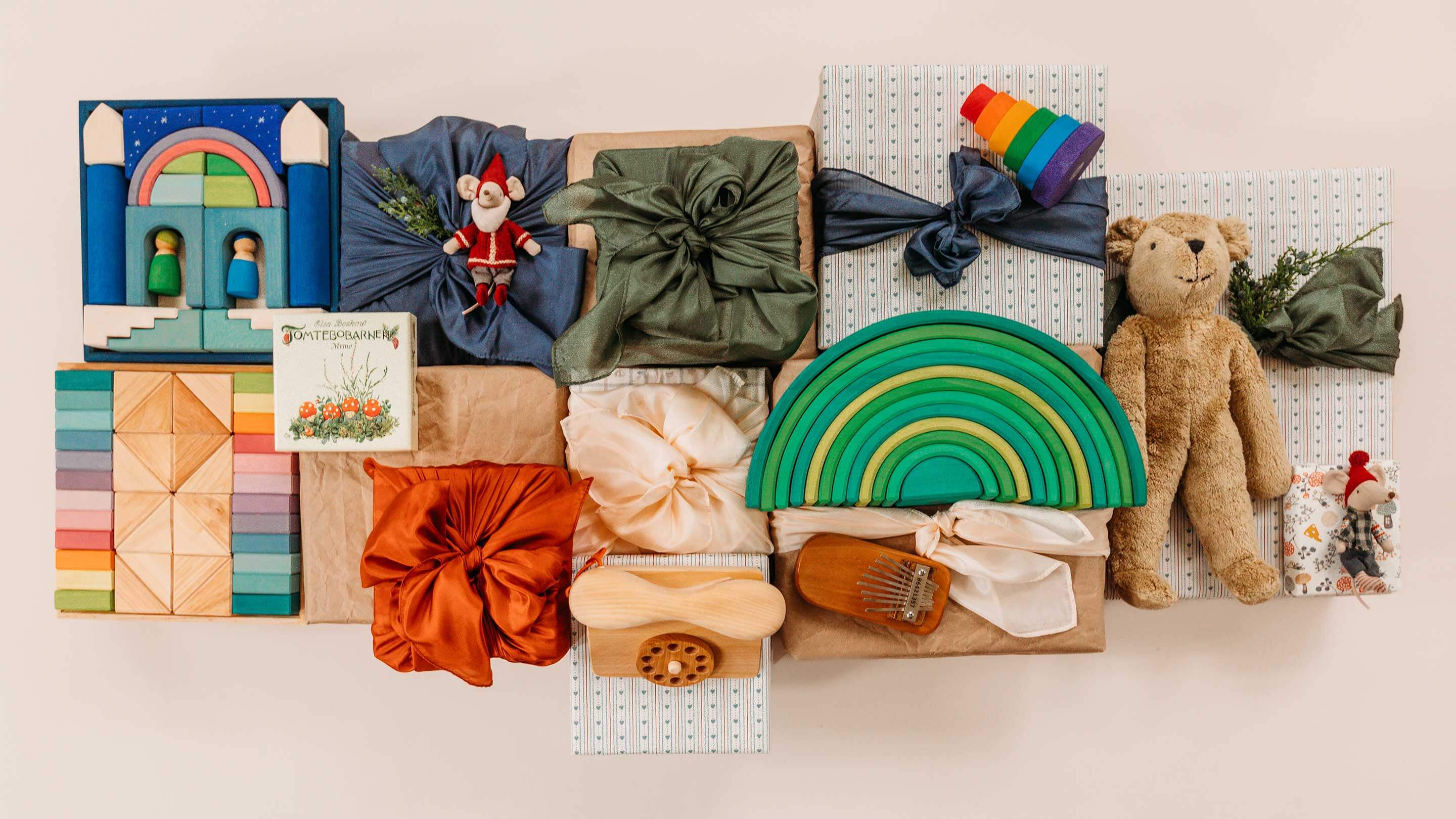 An assortment of toys wrapped in holiday colored play silks and wrapping paper