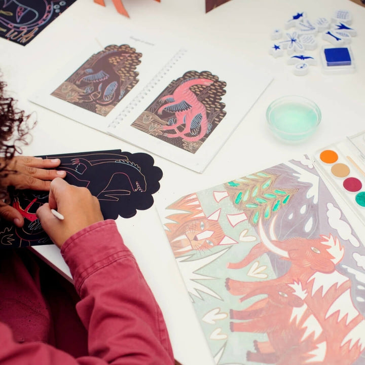 A child works on a scratch card from the Dinosaur World multi-activity craft kit from Djeco.