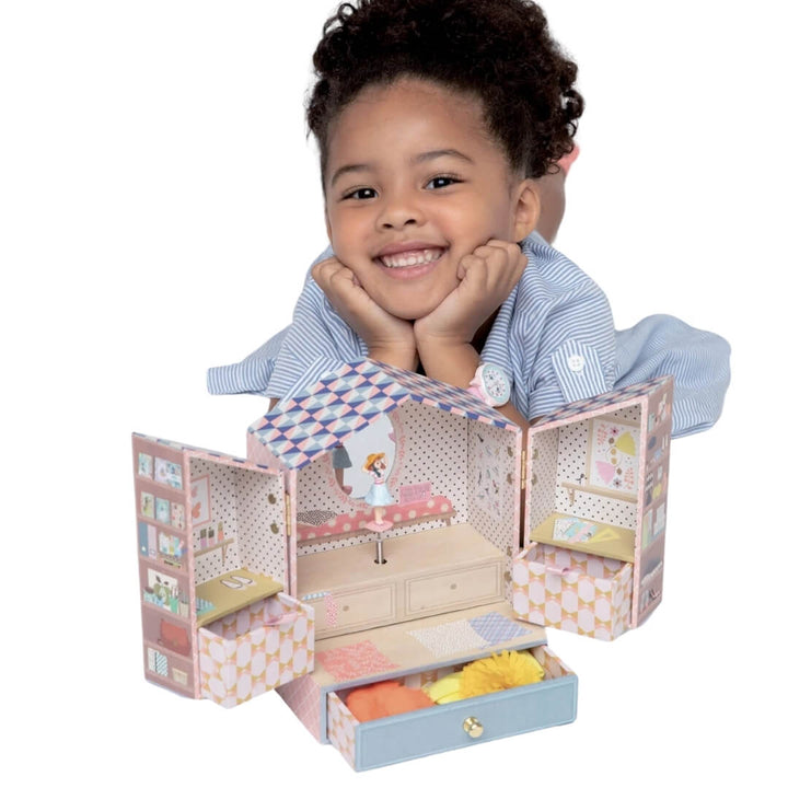 A child smiles next to the open musical jewelry box.