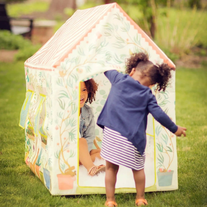 Two children play outside in the Garden House Play Tent by Djeco.