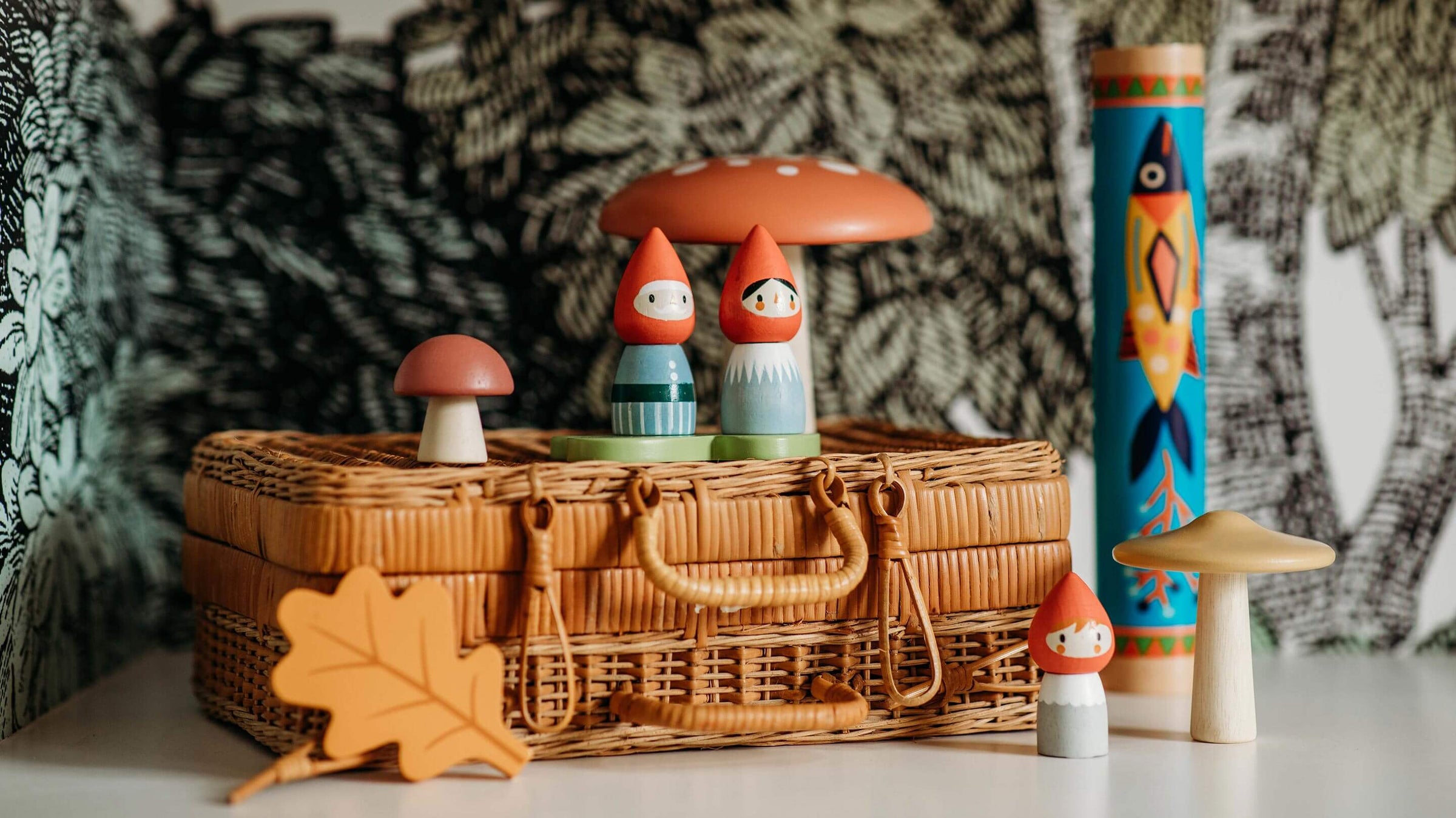 Wooden Gnome nins on a wicker basket with wooden mushrooms and wooden leaf