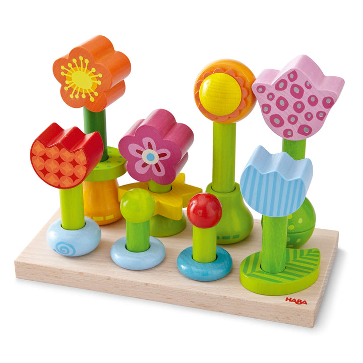 Wooden flowers created using daisy, tulip and sunflower shapes on green cylinders on a peg board