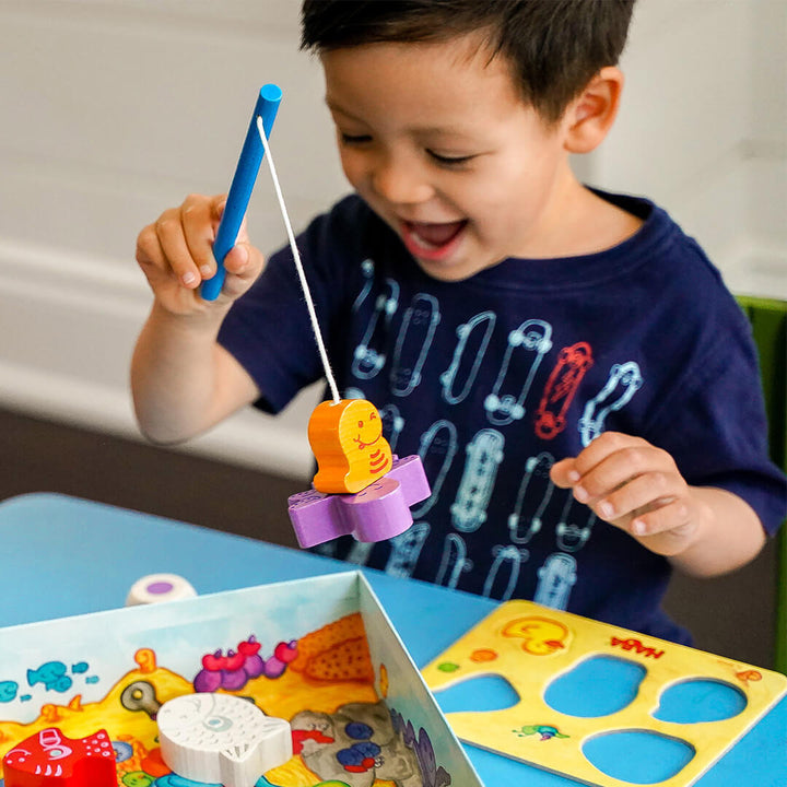 Laughing boy holding a toy fishing rod playing My Very First Games - Here, Fishy, Fishy! Magnetic Game