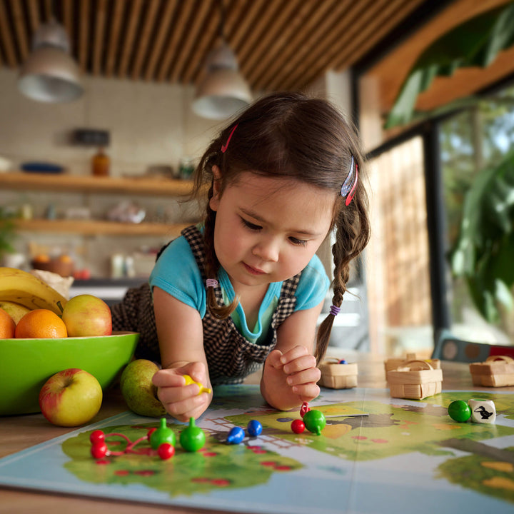 Girl in pigtails playing HABA's Orchard Game on kitchen table