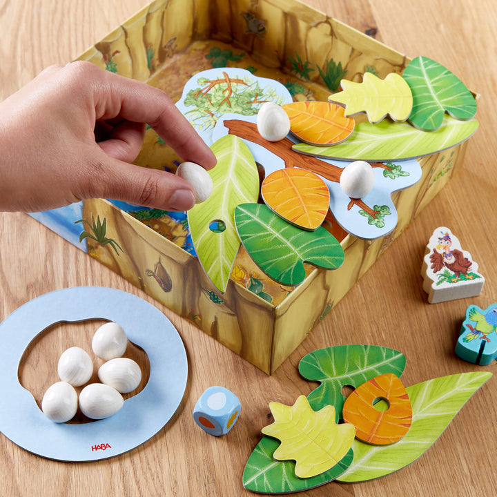 Someone placing a wooden egg onto the leaf in a game of Teetering Treetops from HABA.