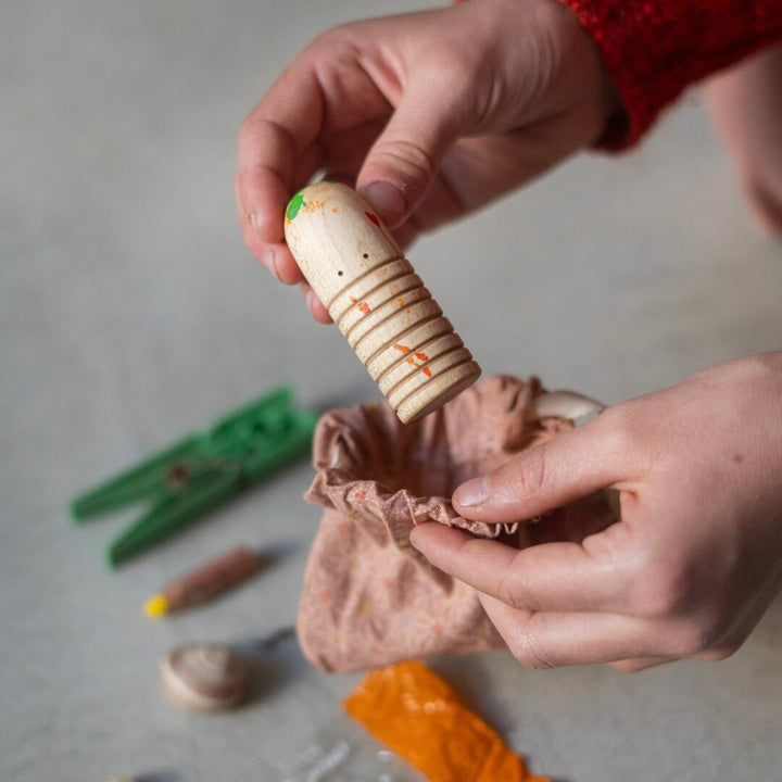 A child holds a wooden figure they painted from the 2024 Grapat Advent Calendar.