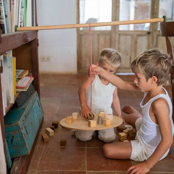 Two children playing with the Grapat Wooden Balance Board with different wooden toys and blocks to  explore balance, motion, and physics through open-ended play and  experimentation.