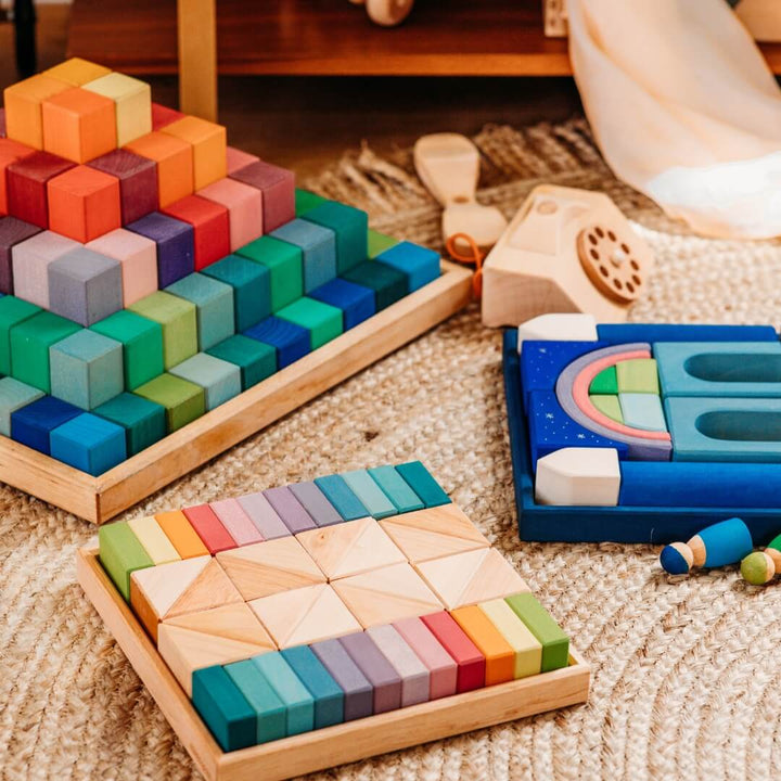 Grimm's Pastel Duo Wooden Block Set on rug next to more Grimm's blocks.