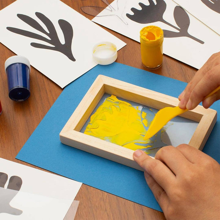 Hands applying paint with yellow applicator to stencil with DIY Screenprint Kit