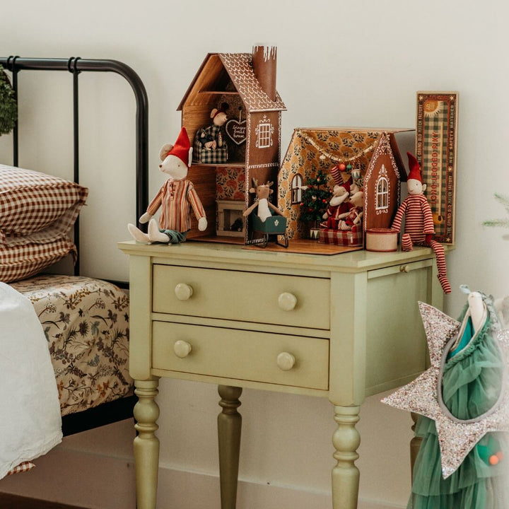 Maileg gingerbread houses sit on a bedside table with assortment of holiday furniture, decorations and mice.