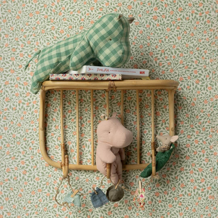 Maileg medium hippo in green gingham laying on a shelf with books and other Maileg toys.