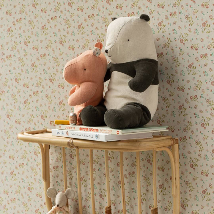 Maileg medium sized stuffed panda bear on a shelf with books and a stuffed hippo.