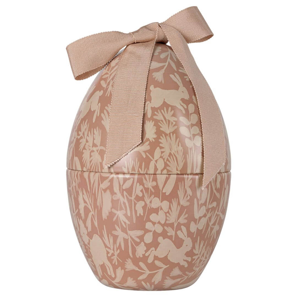 A pink and cream colored metal egg with a Maileg print and ribbon on top.