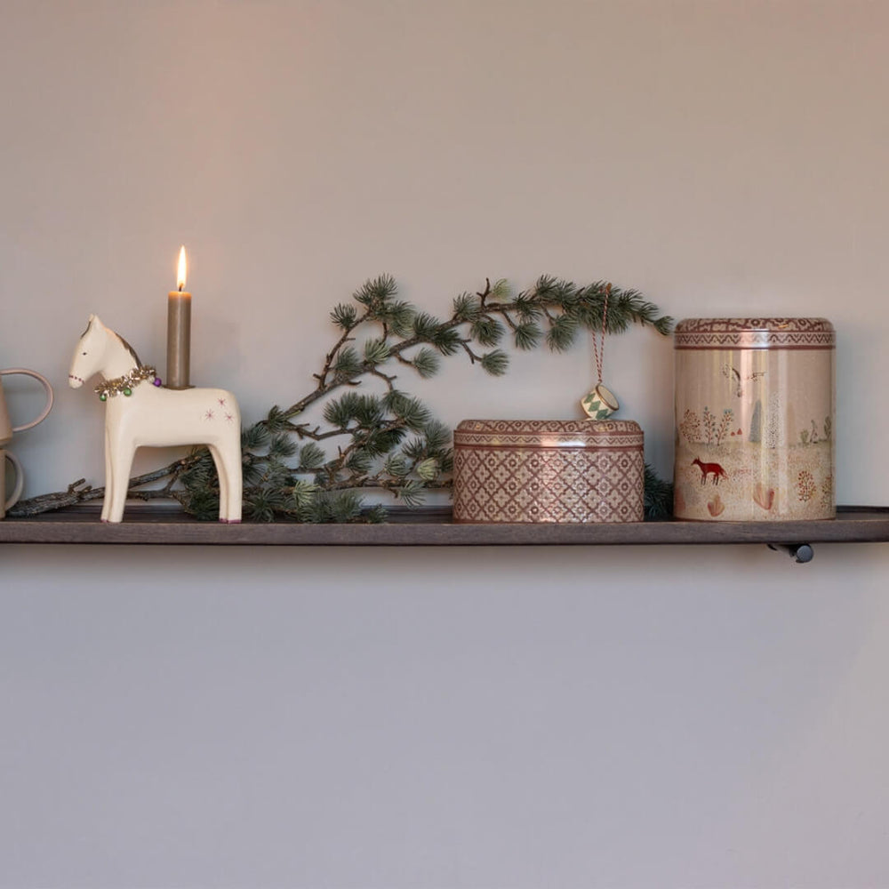 Shelf displaying holiday items including Maileg metal storage tins with a Scandanavian inspired illustration of reindeer.