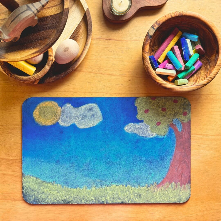 A Waldorf inspired chalk drawing on a smal chalkboard next to a bowl of pastel colored chalks.