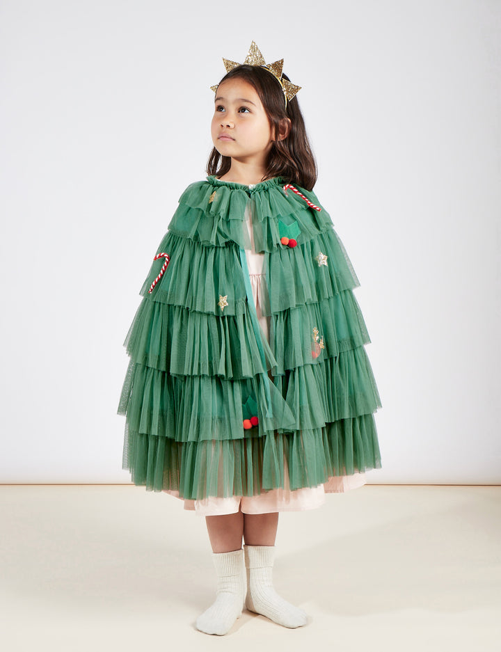 A child dressed as a christmas tree wearing the green tule cape and golden star headband.