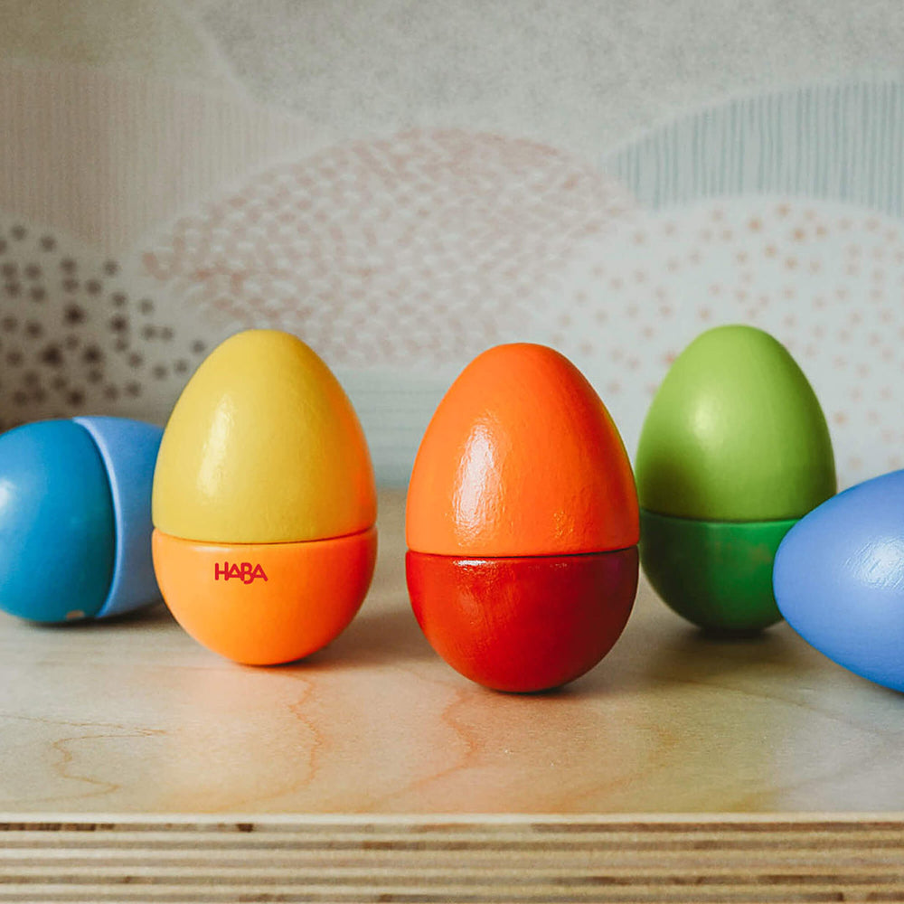 Colorful, wooden, egg-shaped toys arranged on a wooden surface.