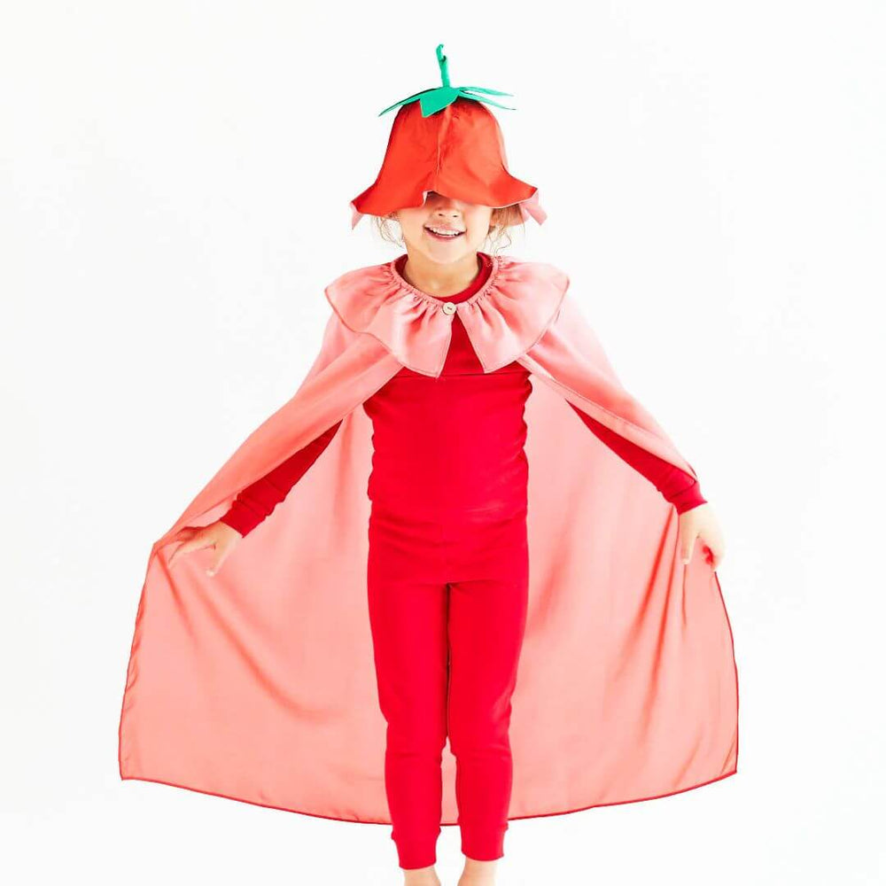 A child wearing a red strawberry hat and pink cape from Sarah's Silks.