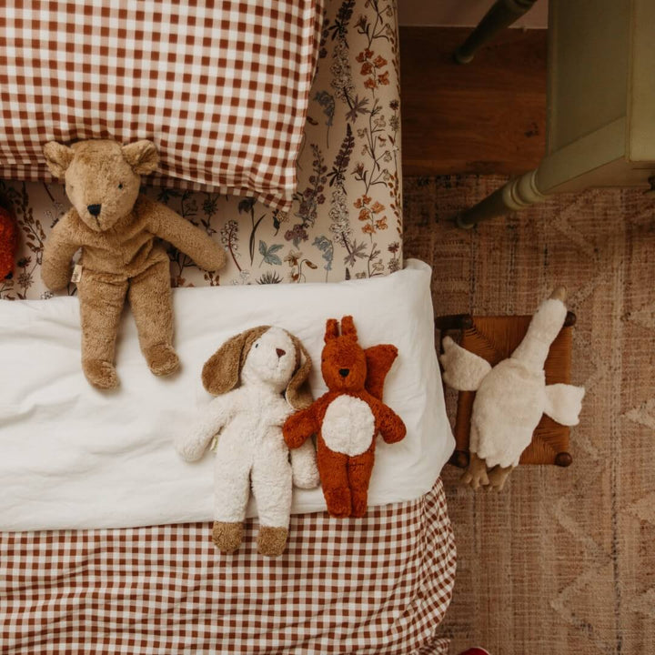 A Senger organic teddy bear, puppy, squirrel and goose in a child's bed.