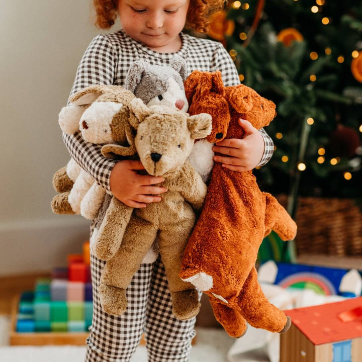 A child holds an armful of organic stuffed animals from Senger, including the organic teddy bear.