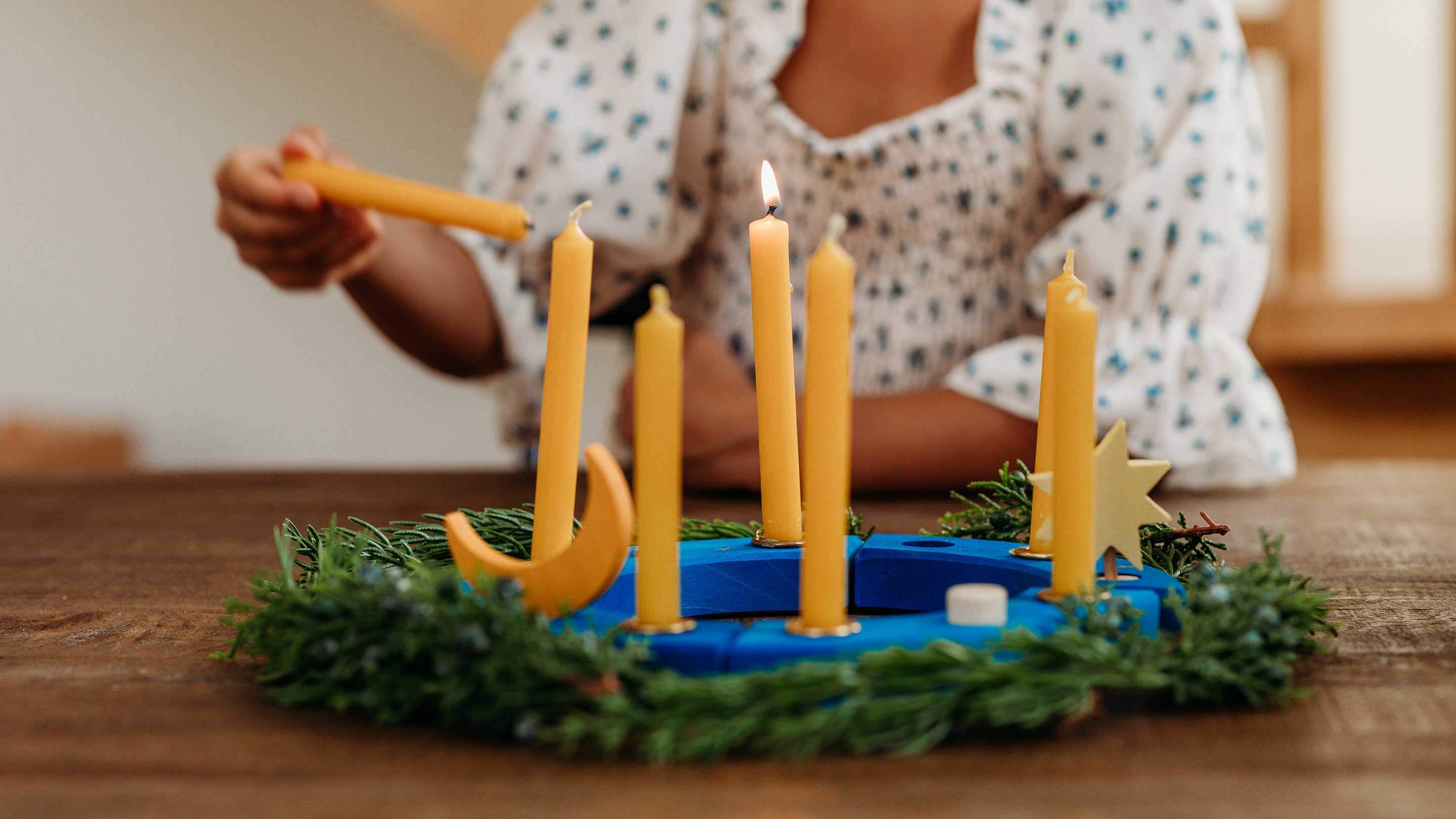 A child lighting the candles on a Bella Luna Toys x Grimm's Over the Moon Birthday Ring